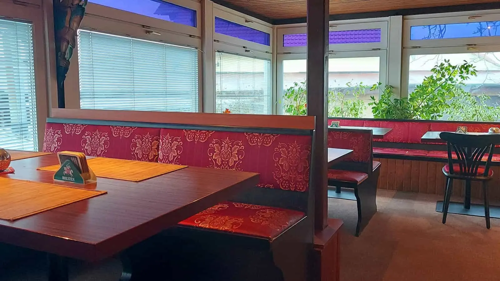 Laid wooden tables against a red wall by the window