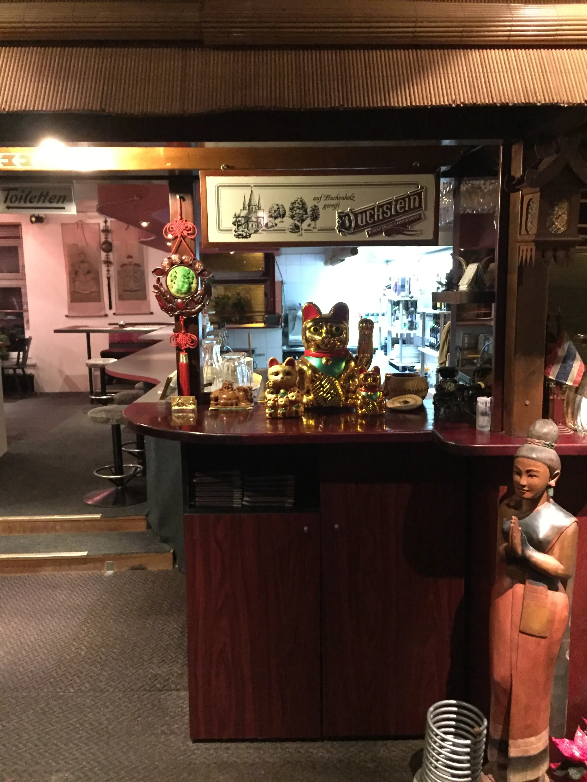 The bar with a wooden figure and shelves of drinks